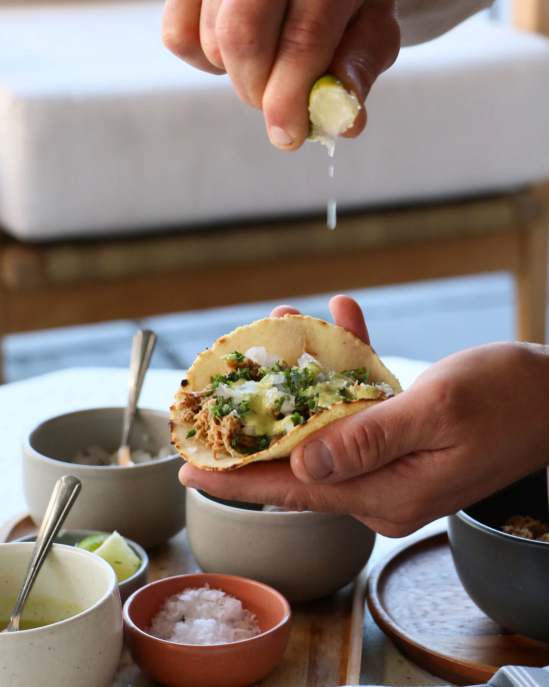 A hand squeezing a lime over a taco.