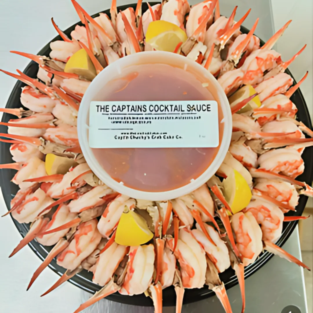 A platter of shrimp cocktail and crab fingers with cocktail sauce.