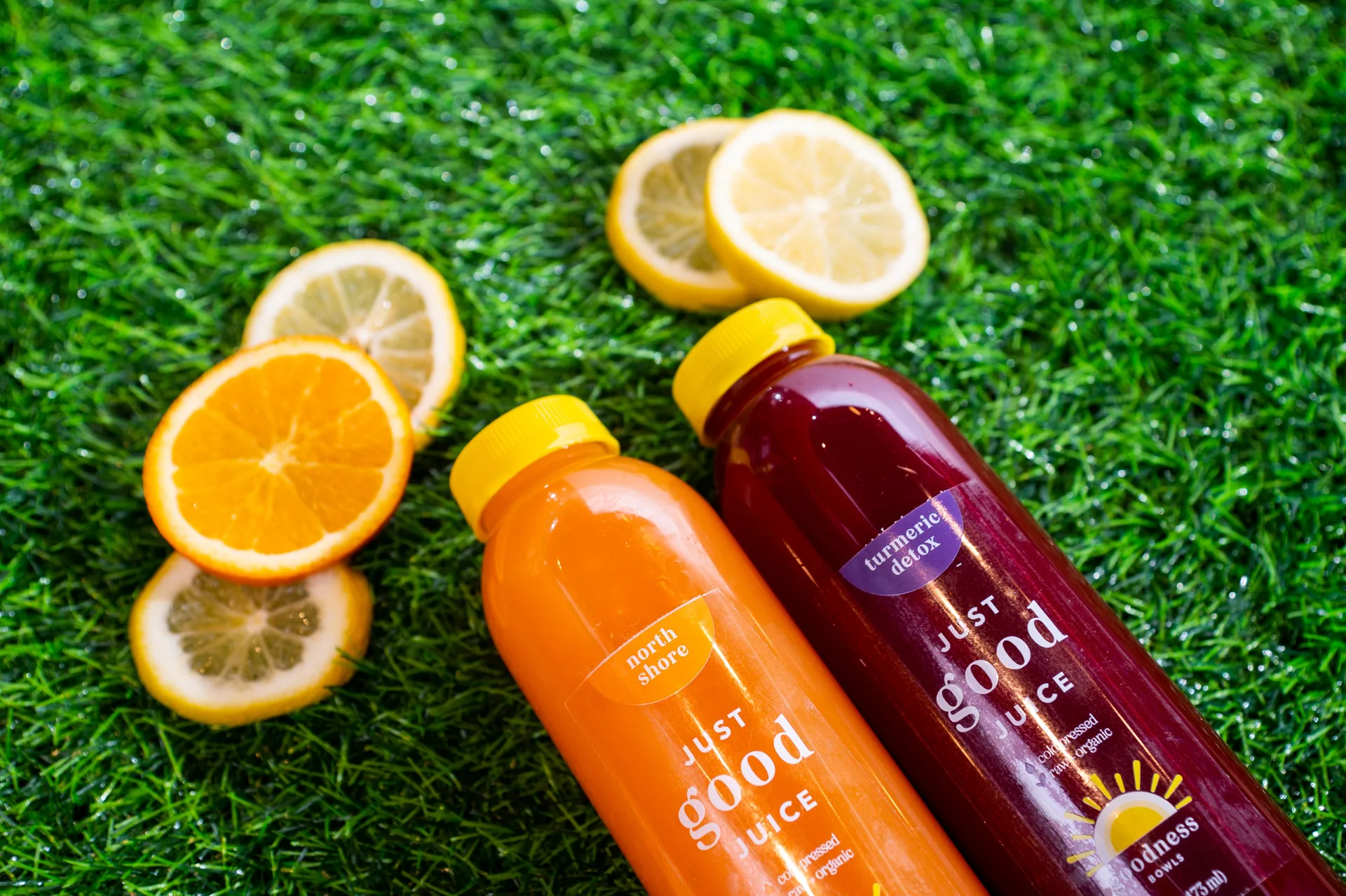 Orange and red juice with lemons on grass.