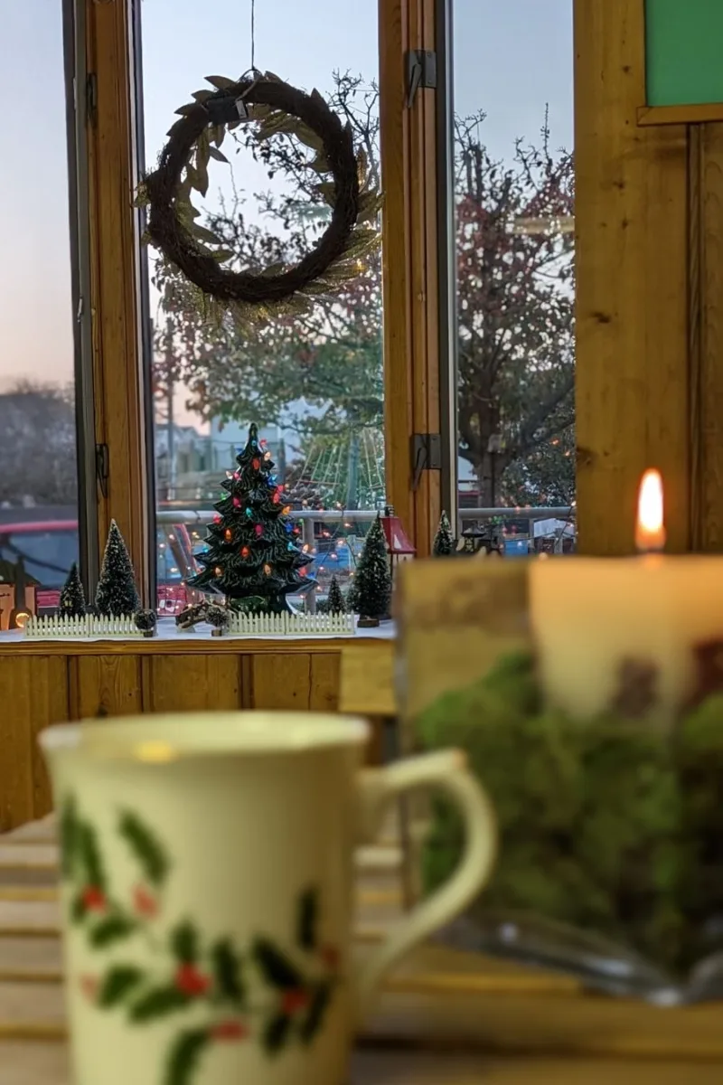 A Christmas display and Christmas coffee cup, with a holiday wreath in the window.