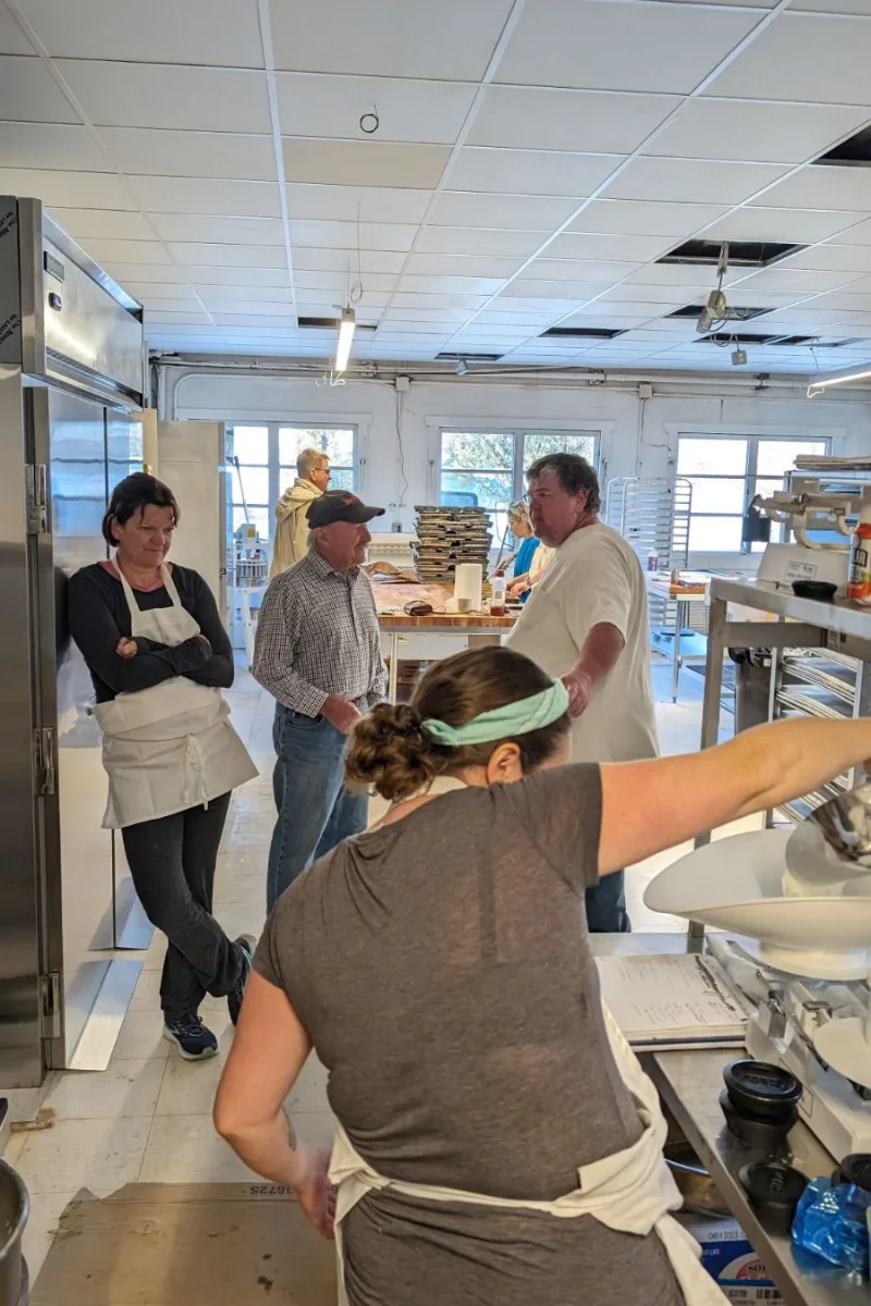 People standing in the back of a bakery.