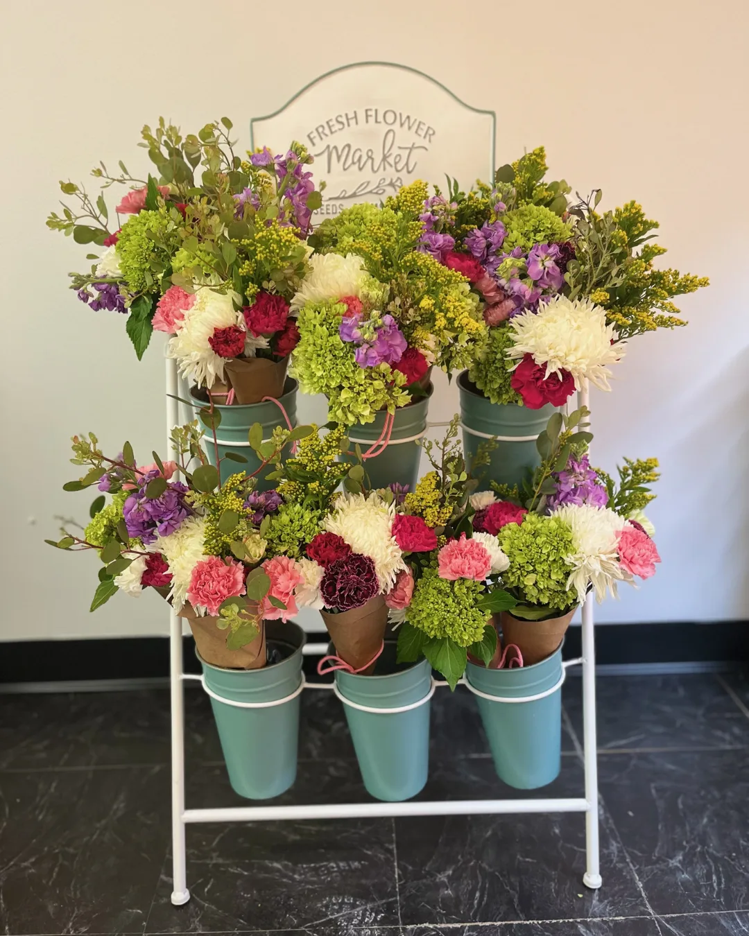 Six bouquets of fresh-cut flowers displayed on a stand. 