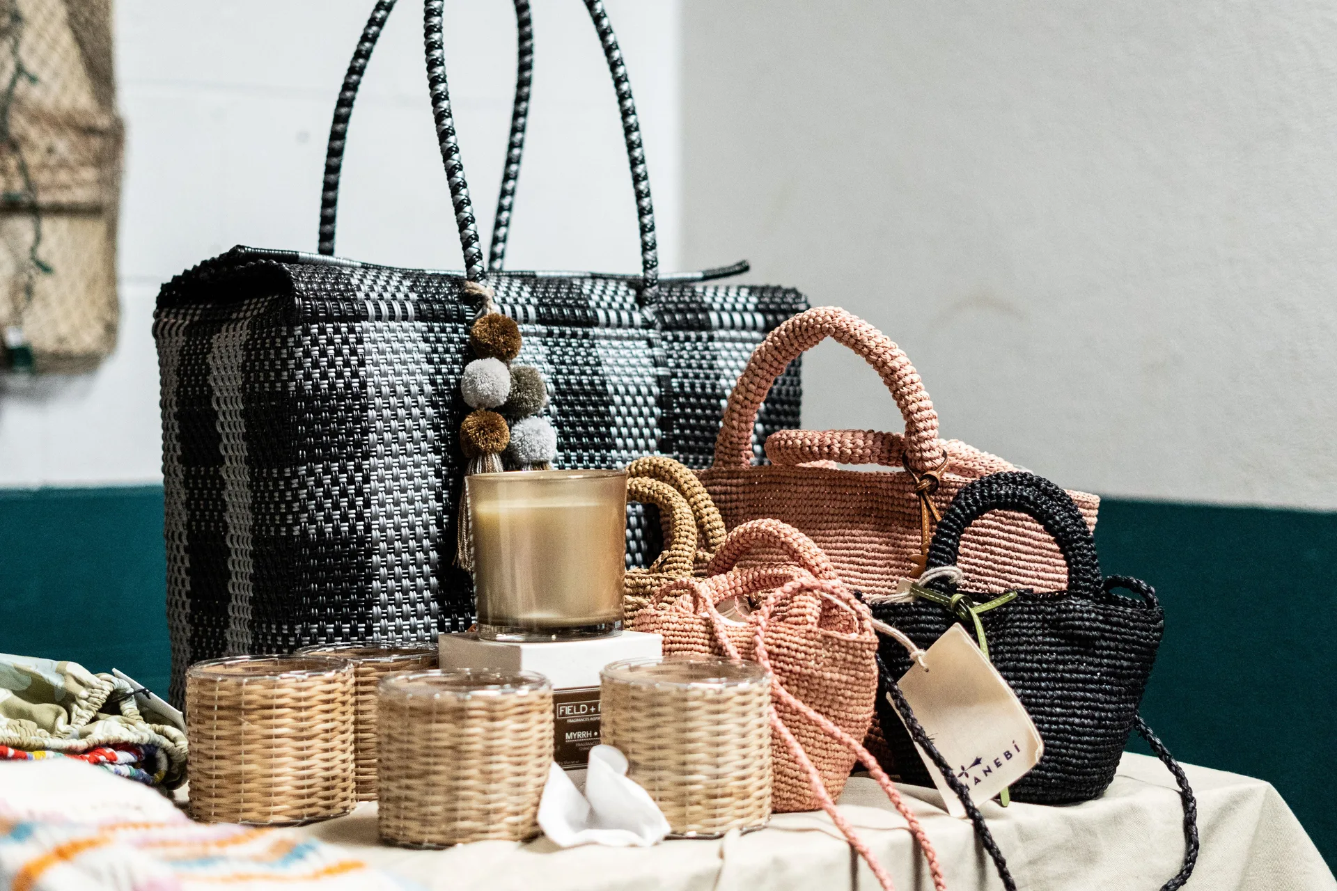 A display of handbags and candles on a table. 