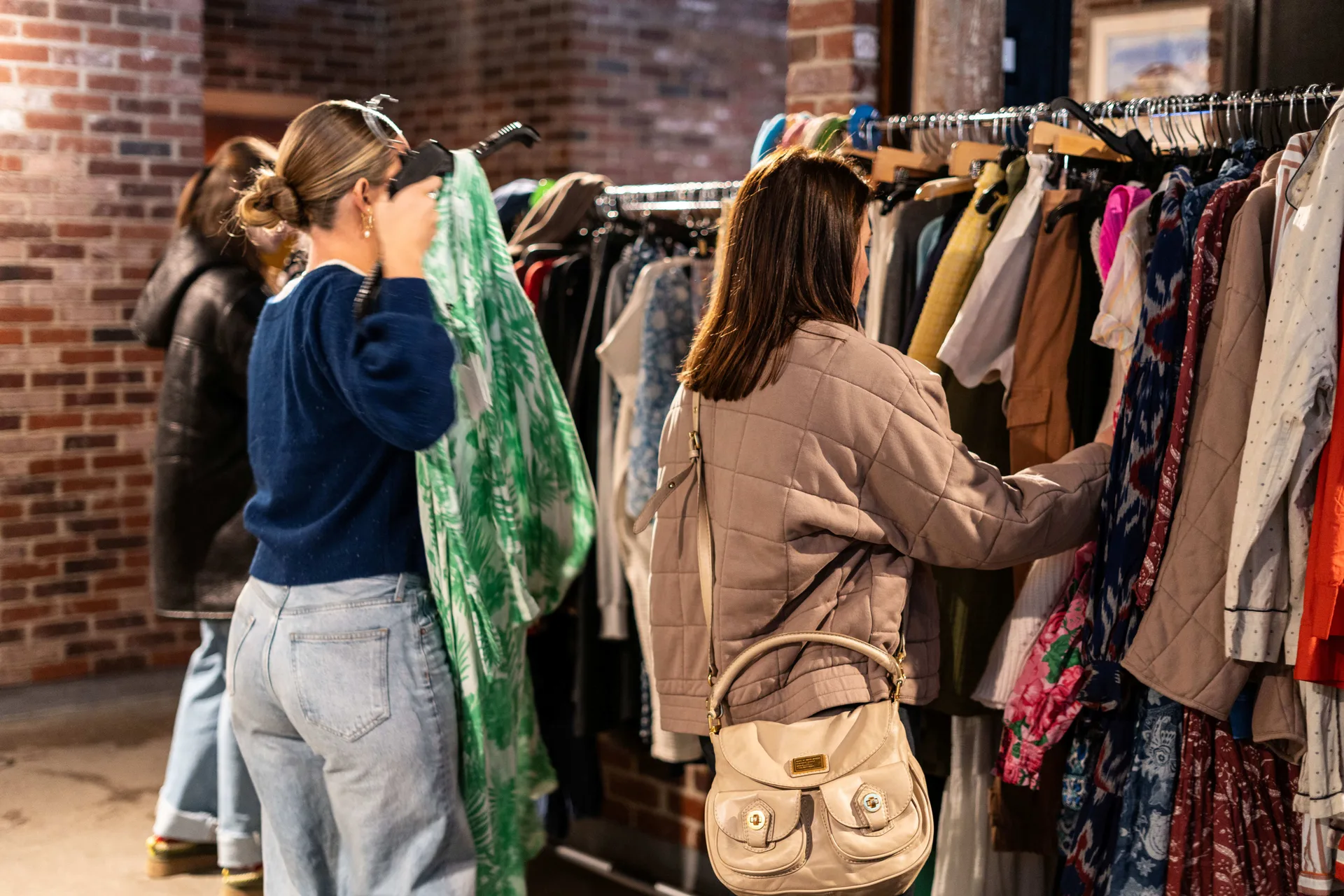 Two women shopping through a rack of clothes.