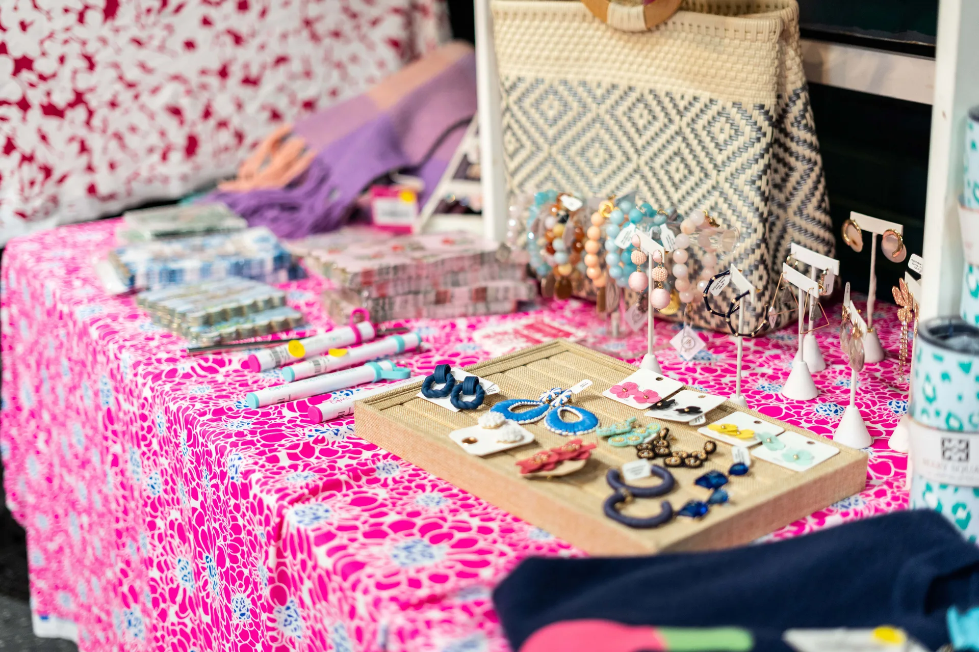 A jewelry display on a table covered with a pink tablecloth.