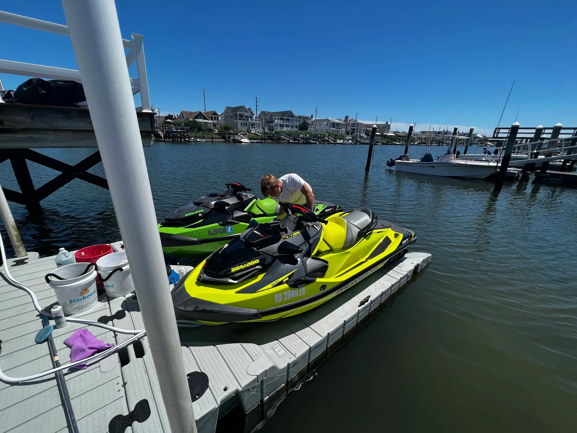 Starboard Cleaning employee cleaning a jet ski that is sitting on a dock.