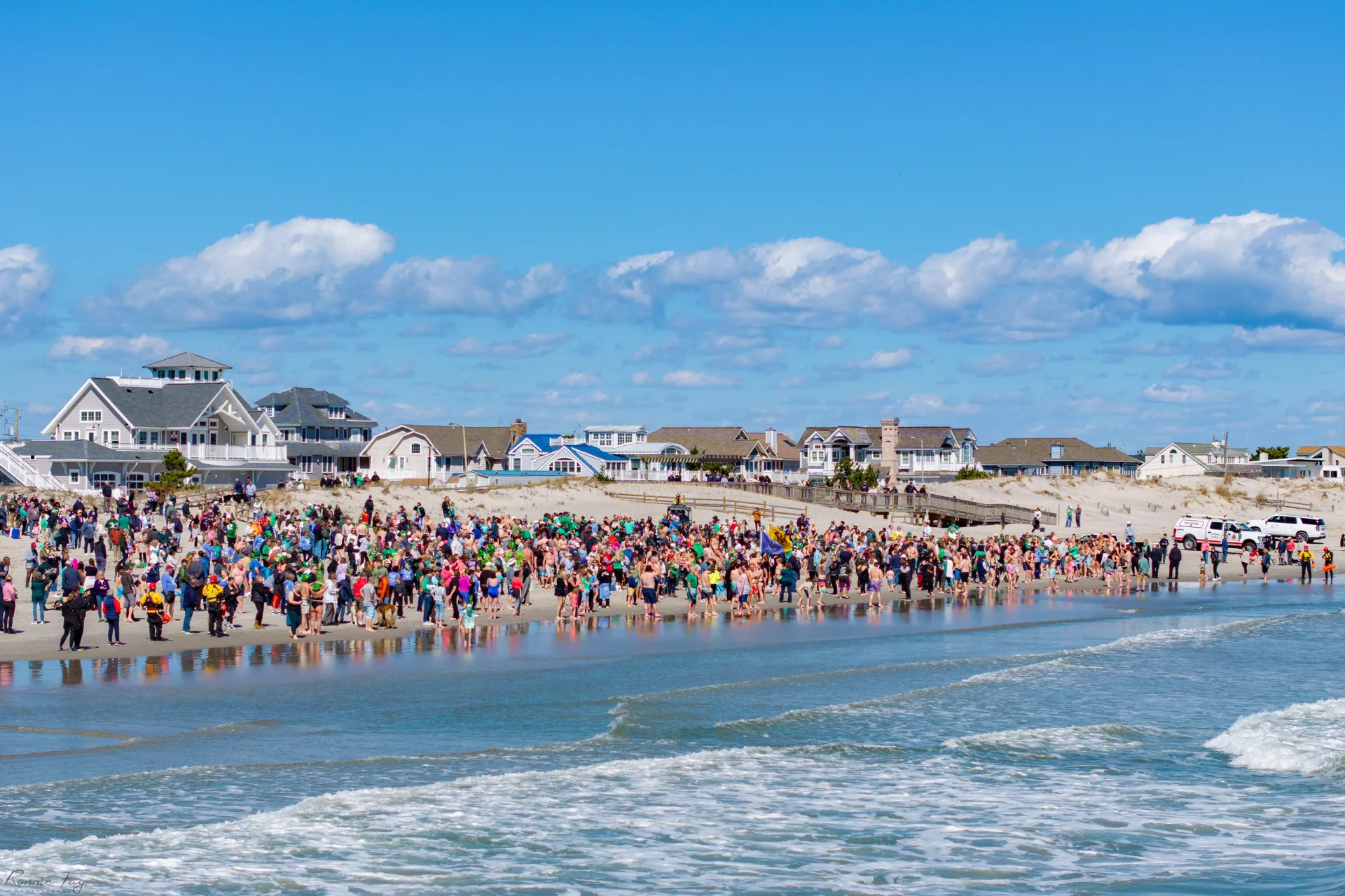 A crowd of people standing at the edge of the ocean.