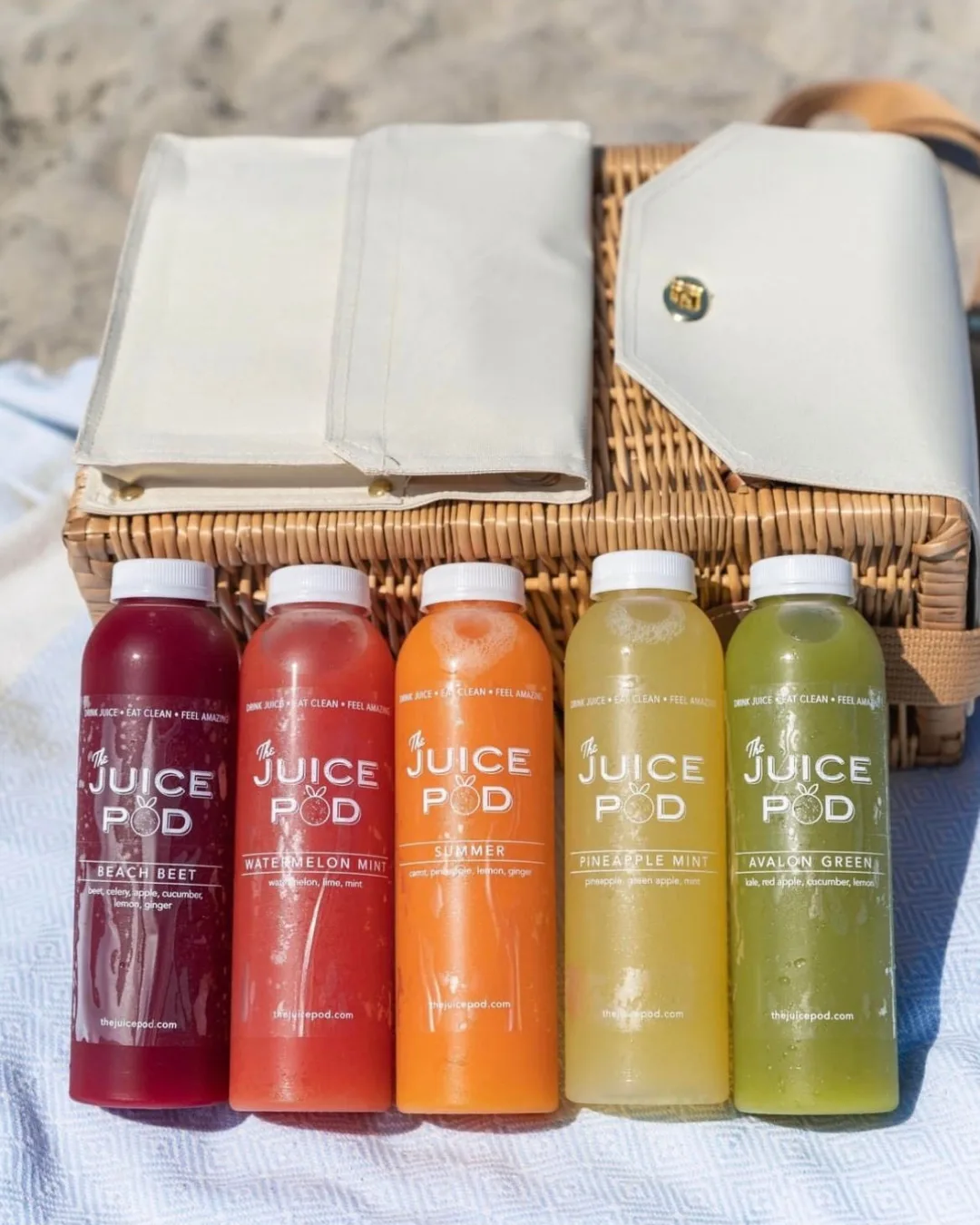A line of cold-pressed juices in a variety of colors - purple, red, orange, yellow, and green. 